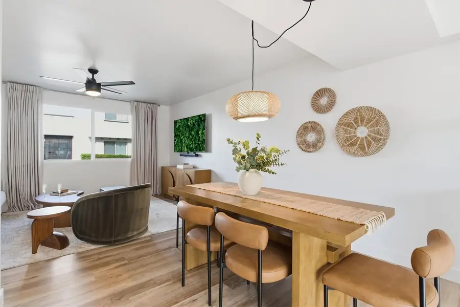 Dining table for six under a woven pendant light at Hideaway, with the living room and patio doors beyond