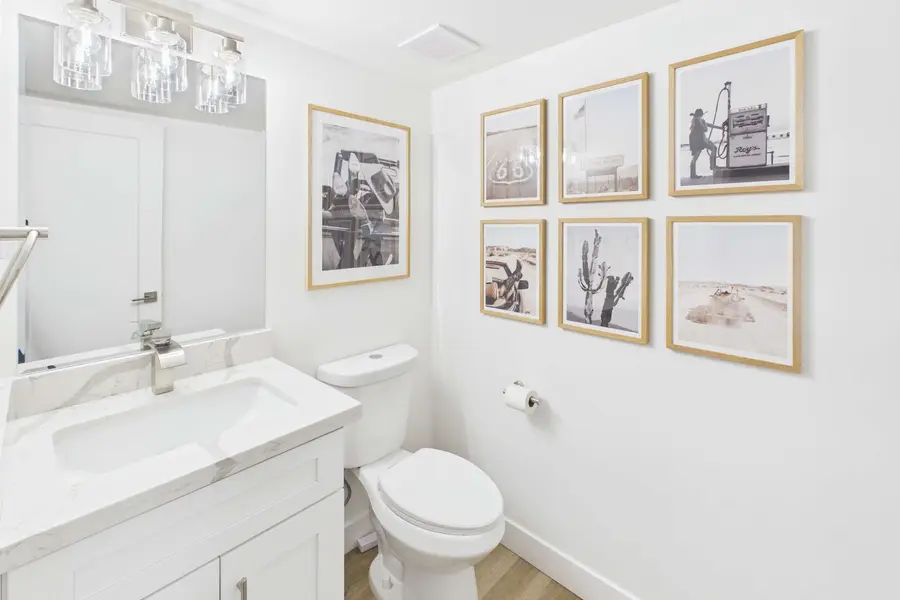 Main-level half bathroom at Hideaway with a marble-topped vanity and a gallery wall of framed desert photographs