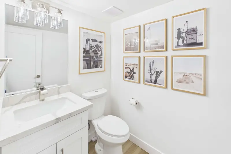 Main-level half bathroom at Hideaway with a marble-topped vanity and a gallery wall of framed desert photographs