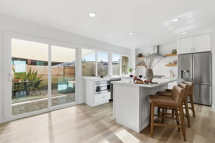 Remodeled kitchen at Hideaway with stainless steel appliances, quartz counters and an island with three bar stools