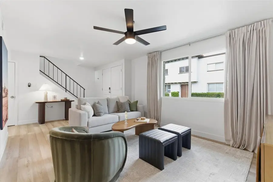 Living room at Hideaway with sofa, armchair, staircase and the front entry, windows facing the community lawn