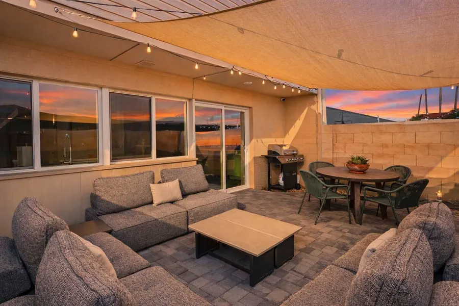 Private patio at Hideaway with sectional seating and an outdoor dining table under string lights at sunset