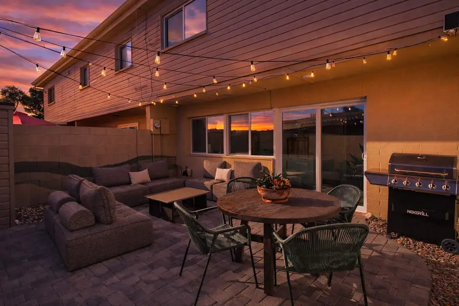 Private patio at Hideaway at dusk with string lights over the sectional, the dining table and the grill
