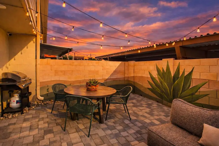 Patio dining table, gas grill and agave at Hideaway with the desert mural painted along the block wall