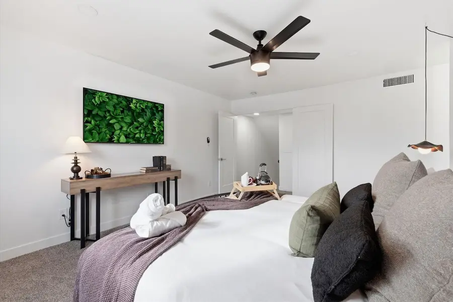 Primary bedroom at Hideaway from the doorway: king bed, wall-mounted smart TV, console table and ceiling fan